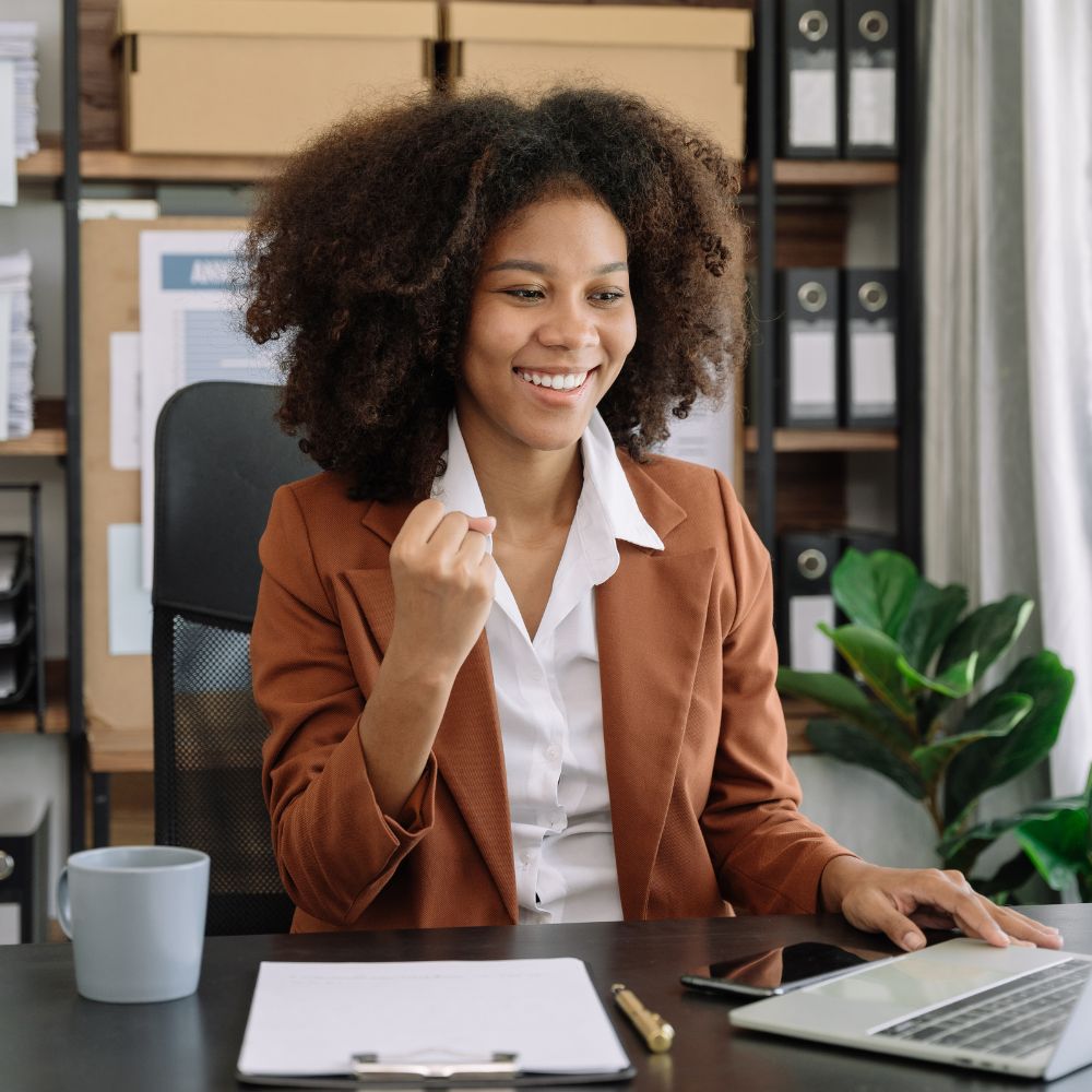 Woman in suit smiling sitting at her desk